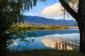 Lake in the mountains. Old wooden pier for fishing. Beautiful nature, reflection of clouds and mountains in blue water. Kyrgyzstan