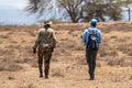 Armed guard and a man tourist on a walking safari on Crescent Island look for wildlife