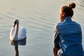 On the lake near the girl the swan gracefully opened its wings