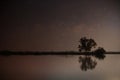 Lake in the night with the stars in the sky and the reflection of the trees and the sky.