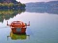 Lake Orestiada, Kastoria, Greece, boat and reflection on calm water. Trees and mountains mirroring on water surface