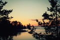 Lake and pine trees. Lonesome fisherman on the bank. Royalty Free Stock Photo