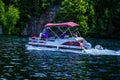 Boaters on pontoon boat enjoy summer day on Lake Placid in New York State`s Adirondack Mountains