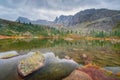 Lake Raduzhnoe in front of rocks among the taiga and large stones under storm clouds in Ergaki