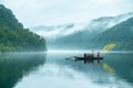 Lake with reflections and a small boat with foggy mountains on the background