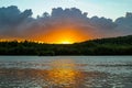 Lake, river summer sunset. Bright orange sun behind clouds, forest. Sky water reflection landscape Royalty Free Stock Photo