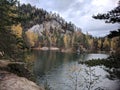 Lake in between rocks and autumnal forest