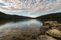 Lake with rocks in the foreground and reflection of sky and surrounding forest