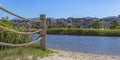 Lake with rope fence and houses on its sandy shore Royalty Free Stock Photo