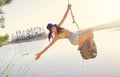 Lake, rope swing and a woman in nature sitting on a tyre for carefree fun or adventure during summer. Water, freedom and Royalty Free Stock Photo