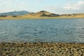 A lake among the sand hills. Beautiful sunny view of the deserted lake. Background of yellow-brown hills and mountains