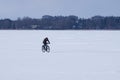 Unidentified male cyclist riding a bike in the winter on the frozen lake