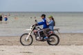 A guy gives a girl a ride on a motorcycle on Lake Shalkar for money. Riding a motorcycle on sandy ground.