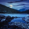 Lake shore with stones near pine forest on mountain at night Royalty Free Stock Photo