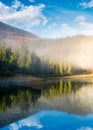 Lake in spruce forest at foggy sunrise Royalty Free Stock Photo