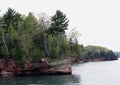 The Lake Superior rocky shoreline in Bayfield, Wisconsin, lined with trees, including Evergreens and Birch, in the spring Royalty Free Stock Photo