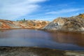 Lake surrounded by bright multi-colored clay hills against a bright blue sky. Ural Mars