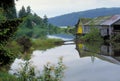 Lake surrounded by greenery with an old barn reflecting on the water with hills on the background Royalty Free Stock Photo