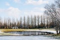 A lake with a table with benches, in a snow-covered park in Reykjavik, Iceland