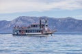 Sternwheeler with tourists on a lake with mountain landscape in background. Royalty Free Stock Photo