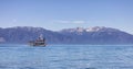 Sternwheeler with tourists on a lake with mountain landscape in background. Royalty Free Stock Photo