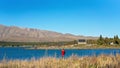 TOURISTS STANDING ON SHORE OF LAKE TEKAPO PHOTOGRAPHING THE CHURCH OF THE GOOD SHEPHERD, NEW ZEALAND Royalty Free Stock Photo