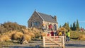 TOURISTS PHOTOGRAPHING THE STONE MEMORIAL CHURCH OF THE GOOD SHEPHERD ON LAKE TEKAPO, NEW ZEALAND