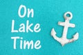 On lake time message on weathered anchor on a turquoise glitter paper