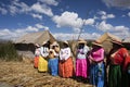 lake titicaca floating islands uros indigenous women in long colored skirts with straw hats and braids waiting for tourists stops