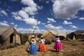 lake titicaca floating islands uros indigenous women in long colored skirts with straw hats and braids waiting for tourists stops