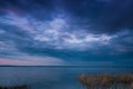 Lake under the stormy sky. calm water, dark maroon ebony