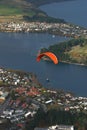 Tandem paraglider flying over lakeside town Royalty Free Stock Photo