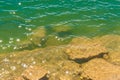 Lake water and stone shore background with sunlight reflection t