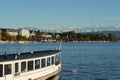 Lake Zurich in early October with a boat and the silhouette of the city on the left bank with small boats anchored on the lake.