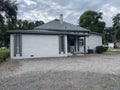 A vintage office style home with gravel yard on a cloudy day