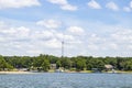 Lakeside homes and boat docks with trees and a transmitter tower in the background under a blue sky with fluffy clouds Royalty Free Stock Photo