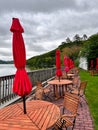 lakeside picnic tables (overcast cloudy skies) closed red umbrella, chairs, railing (scenic dining)