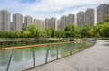 Lakeside plank-paved footbridge before storied apartments in sun