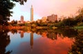 Lakeside scenery of Taipei 101 Tower among skyscrapers in Xinyi District Downtown at dusk with view of reflections on the pond