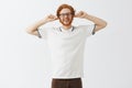 Lalala cannot hear you. Childish and carefree happy young redhead guy with beard in glasses and white polo shirt closing Royalty Free Stock Photo