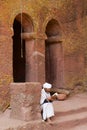 Pilgrim reads bible at the entrance to the unique monolithic rock-hewn church in Lalibela, Ethiopia. UNESCO World Heritage site.