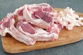 Lamb chopRaw lamb chops and fat on a olive wood cutting board on a grey abstract background. Healthy cooking concept.