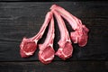 Lamb chops raw meat on bone, on black wooden table background, top view flat lay, with copy space for text Royalty Free Stock Photo