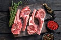 Lamb chops raw meat on bone with salt, pepper and herbs. Black wooden background. Top view Royalty Free Stock Photo