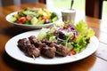 lamb kebabs on white plate, mixed salad on the side