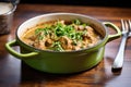 lamb korma in a brass pot, garnished with cilantro, on a wooden table