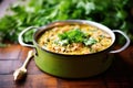 lamb korma in a brass pot, garnished with cilantro, on a wooden table