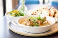 lamb korma in a ceramic dish, yogurt dollop, with naan on the side