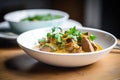 lamb korma plated elegantly with a sprig of coriander, close-up