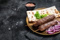 Lamb meat kofta kebab, onion and flat bread on plate. Black background. Top view. Copy space Royalty Free Stock Photo
